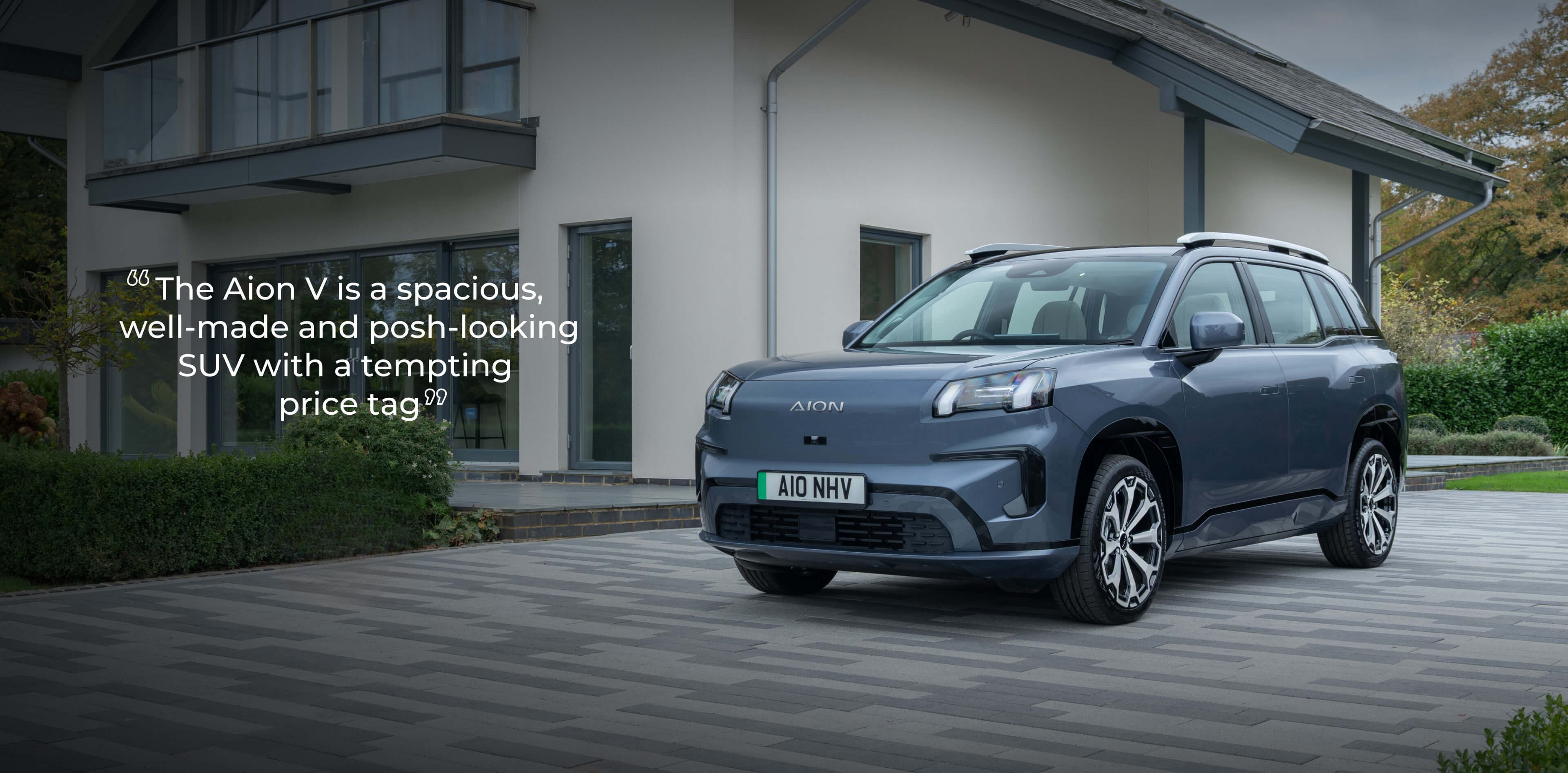 AION V driving through a town street at dusk. 317 miles epic range¹, 24 mins rapid charge², 500 litre boot volume, and 8-year warranty*.
